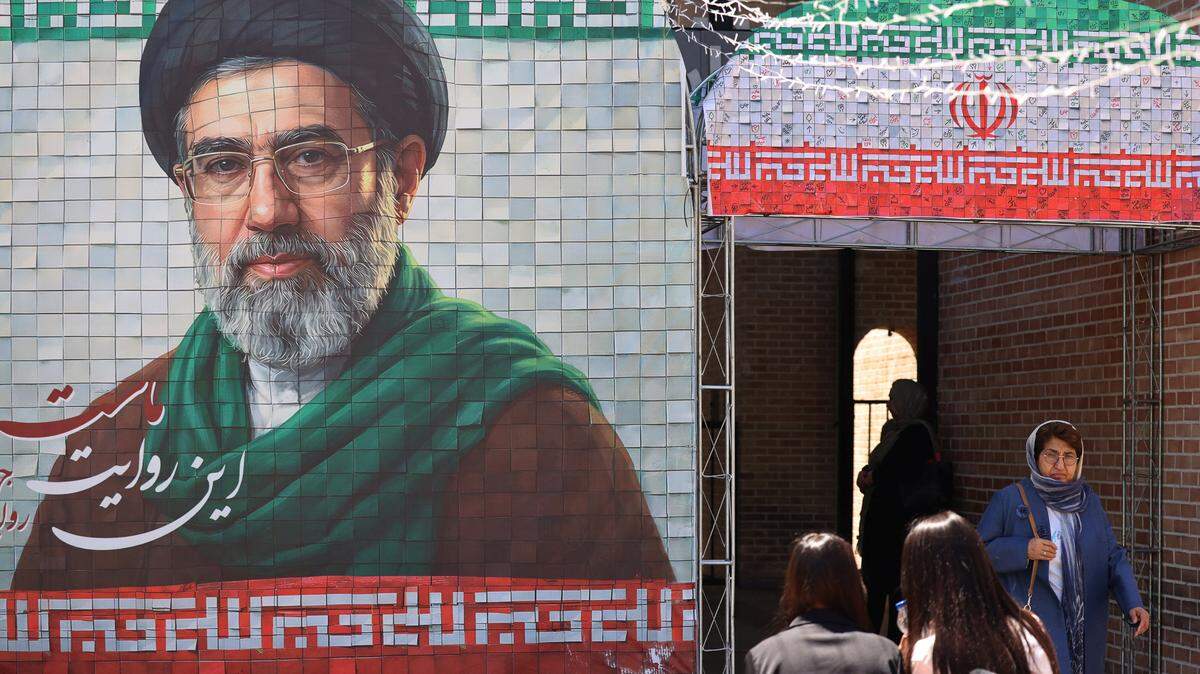 
Gente pasa caminando frente a una gran imagen en mosaico del actual líder de Irán, el ayatolá Mojtaba Jameneí, en la entrada del metro en Teherán el 9 de mayo de 2026. I