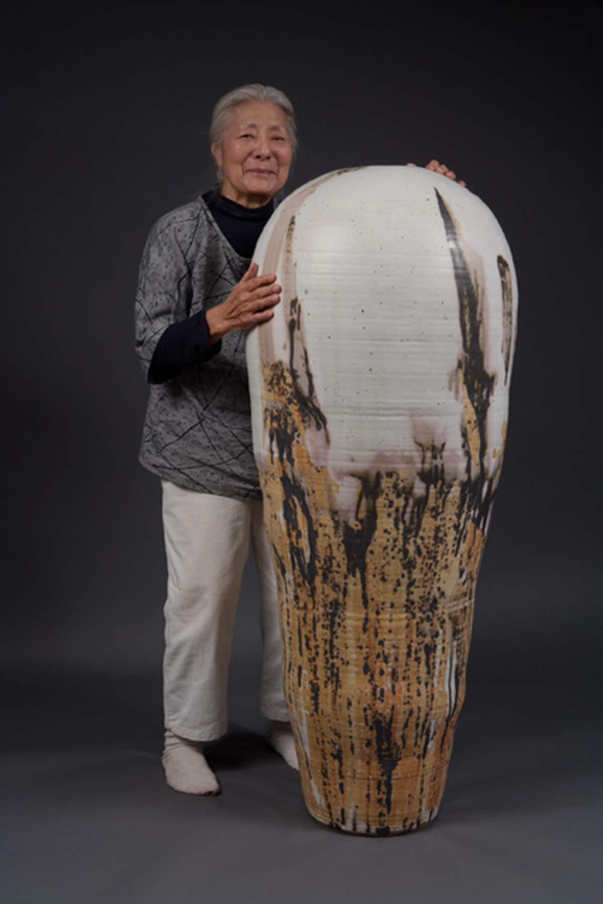 La artista Toshiko Takaezo posando al lado de una de las piezas expuestas en la Bienal de Venecia.