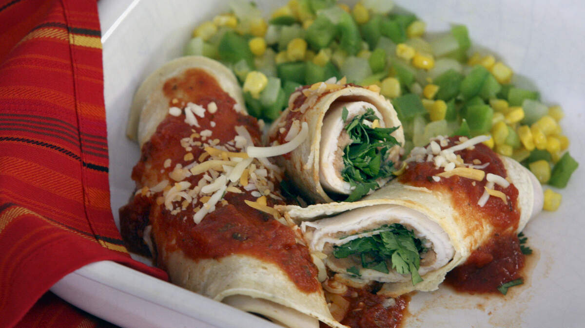 Disfrute estas enchiladas de pavo y refritos. Solo toma 5 minutos hacerlas en el microndas y puede ponerles una salsa picante de tomate para terminar.