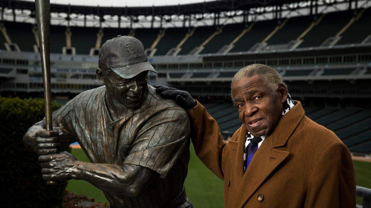 Foto de archivo. El exjugador de los Medias Blancas Orestes Miñoso posa junto a su estatua en el U.S. Cellular Field en Chicago, Illinois, el 14 de noviembre de 2014.
