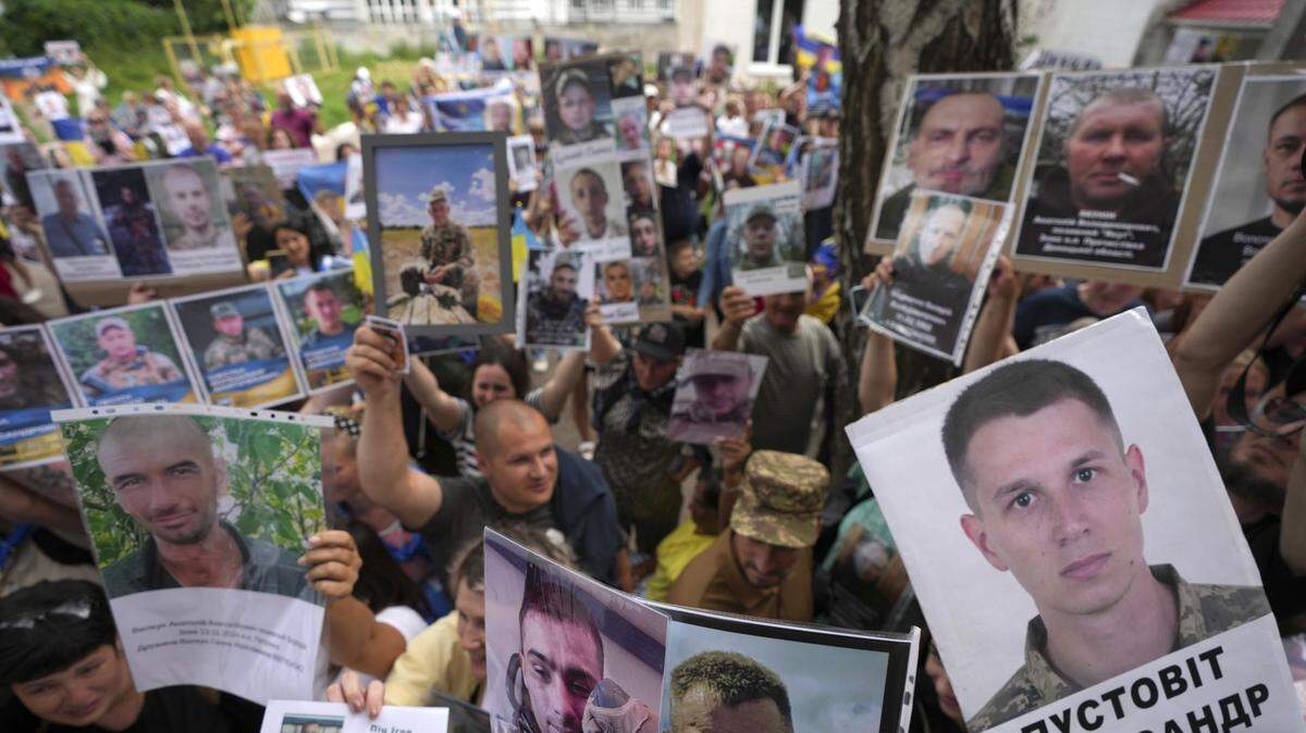 Ucranianos muestran retratos de sus familiares desaparecidos a prisioneros de guerra liberados con la esperanza de que alguien los haya visto, tras un intercambio de prisioneros con Rusia, en un lugar no revelado, el 9 de junio de 2025.