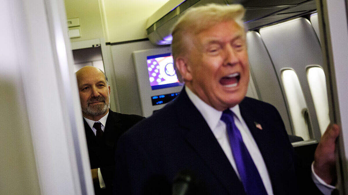 El secretario de Comercio de Estados Unidos, Howard Lutnick, se encuentra detrás del presidente estadounidense Donald Trump mientras este conversa informalmente con los periodistas a bordo del Air Force One el viernes 6 de febrero de 2026, en ruta a Palm Beach, Florida.