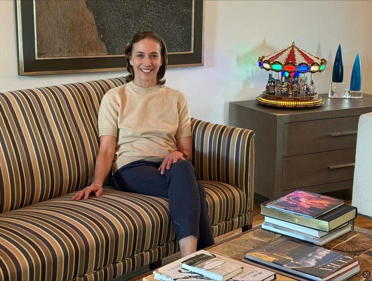 Lourdes López en su casa. Lourdes escogió esta foto porque aparece un libro sobre Cuba en la mesa de centro ubicada justo frente al sofá.