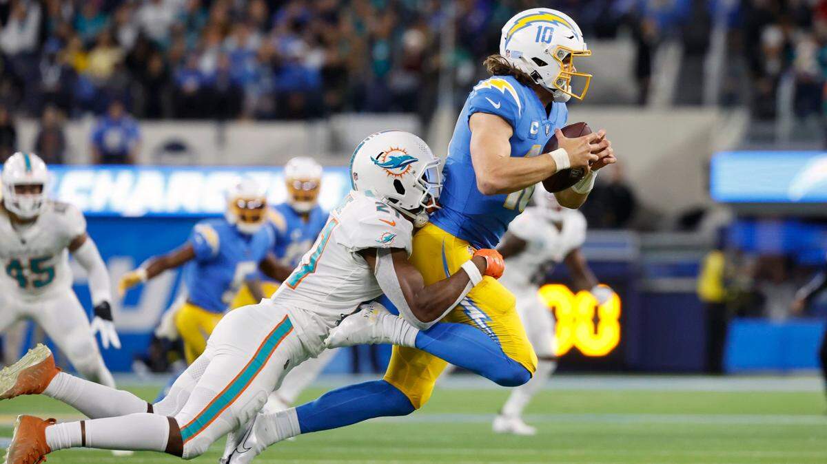 Miami Dolphins safety Eric Rowe tackles Chargers quarterback Justin Herbert in a game held on December 11, 2022 at SoFi Stadium in Inglewood, California.