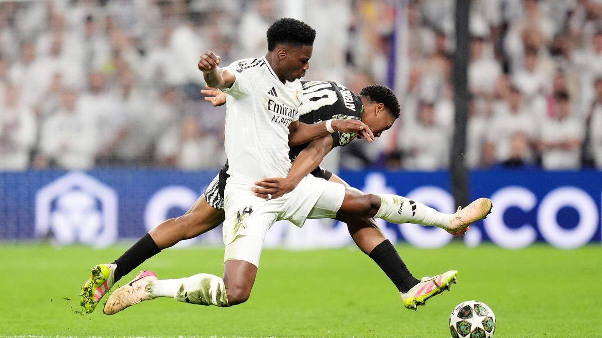 El jugador del Real Madrid Aurelien Tchouameni (izq.) lucha por la pelota con Myles Lewis-Skelly, del Arsenal, en el partido de vuelta de los cuartos de final de la Liga de Campeones, celebrado el 16 de abril de 2025 en el estadio Santiago Bernabéu de la capital española.