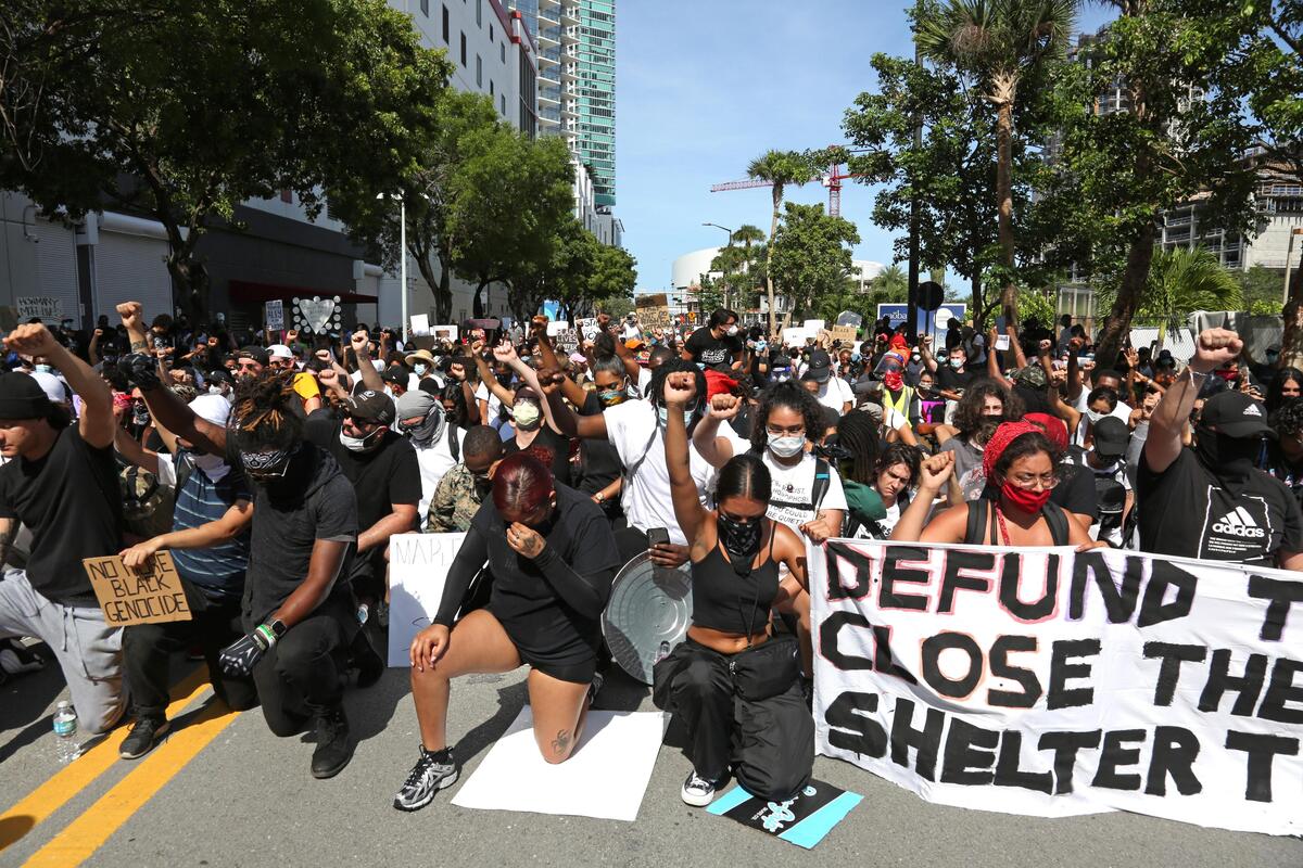 Protesters kneel and hold a moment of silence during a protest in Downtown Miami, Sunday, may 30, 2020