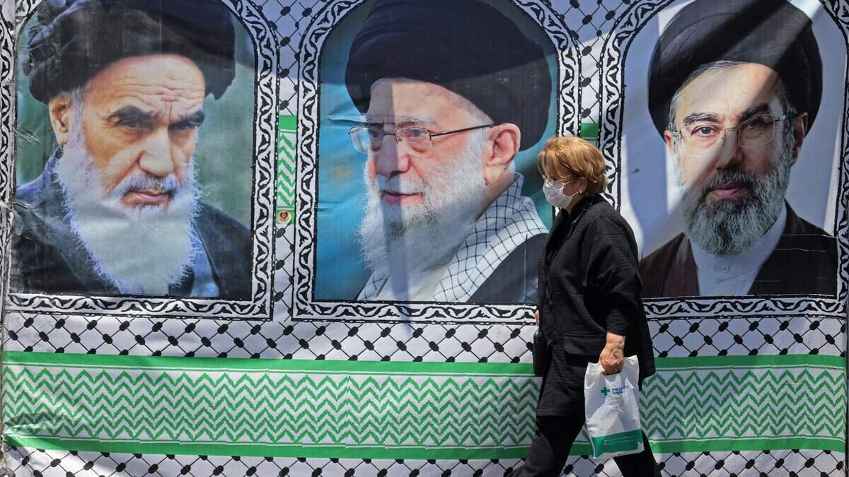 A woman walks past a banner bearing the images of the late founder of the Islamic Revolution supreme leader Ayatollah Ruhollah Khomeini (L), the late Iranian supreme leader Ali Khamenei and his son, the current supreme leader Mojtaba Khamenei (R), erected along a street at the Vanak Square in Tehran on June 10, 2026. Iran's foreign ministry said on June 10 that the United States had damaged the ongoing international diplomatic effort to end the war, after more US strikes on targets in southern Iran. (Photo by ATTA KENARE / AFP via Getty Images) /