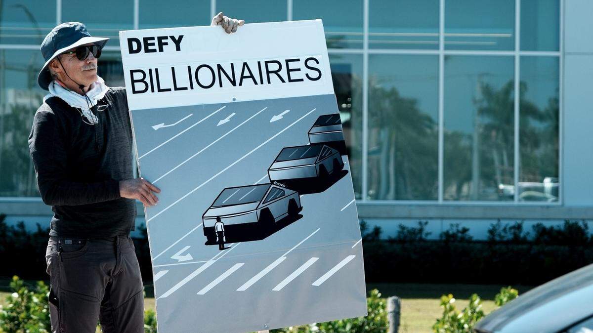 Un hombre sostiene una pancarta que recrea la protesta de la Plaza Tiananmen en China pero con “cybertrucks” de Tesla, para manifestar en contra del billonario Elon Musk, dueño de Tesla, y su poder en el gobierno de Donald Trump, el sábado 15 de marzo de 2025, en Sarasota, Florida.