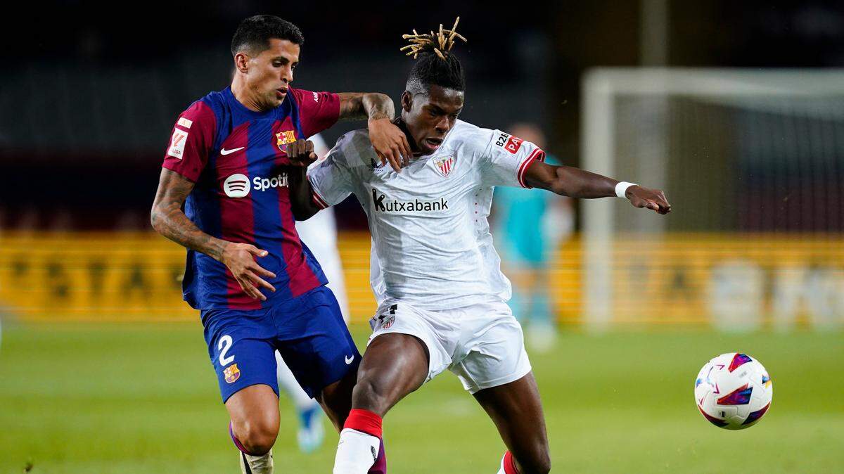El jugador del Athletic Club Nico Williams (der.) disputa el balón con Joao Cancelo, del Barcelona, en el partido celebrado el 22 de octubre de 2023 en Barcelona.