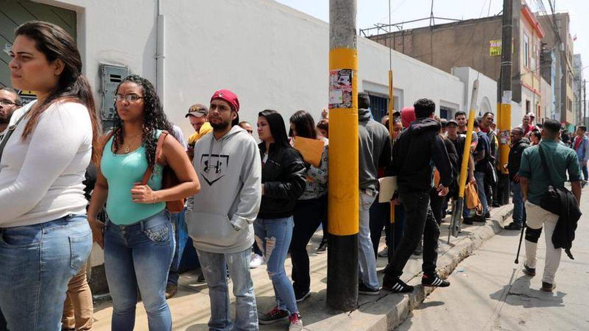 Decenas de migrantes venezolanos hacen cola para tramitar el Permiso Temporal de Permanencia que les permita quedarse en Perú, el 20 de agosto del 2018, en los exteriores de la Superintendencia Nacional de Migraciones de Lima.