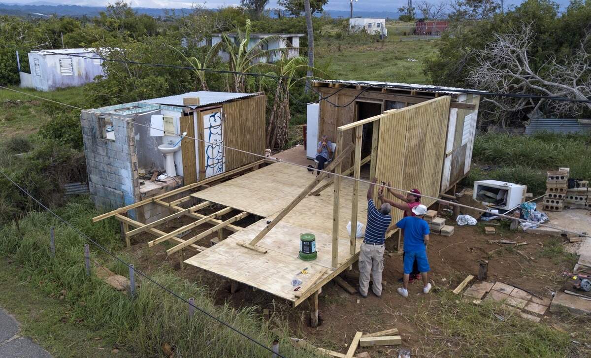 Lidia Reyes observa a familiares reconstruir su casa un año después que el huracán María destrozó la vivienda en Islote, Arecibo, Puerto Rico.