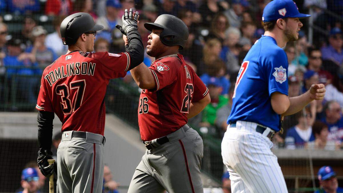 Yasmany Tomas (centro) es felicitado por su compañero de equipo Kelby Tomlinson tras anotar una carrera para los Diamondbacks en un partido de pretemporada ante los Cachorros, celebrado el 26 de febrero de 2019.