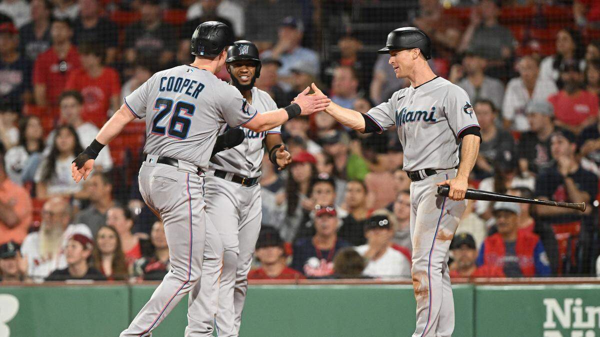 El primera base de los Marlins Garrett Cooper (izq.) festeja con Bryan De La Cruz (centro) y Joey Wendle tras anotar una carrera en el sexto inning del partido ante los Medias Rojas, celebrado el 28 de junio de 2023 en Boston.