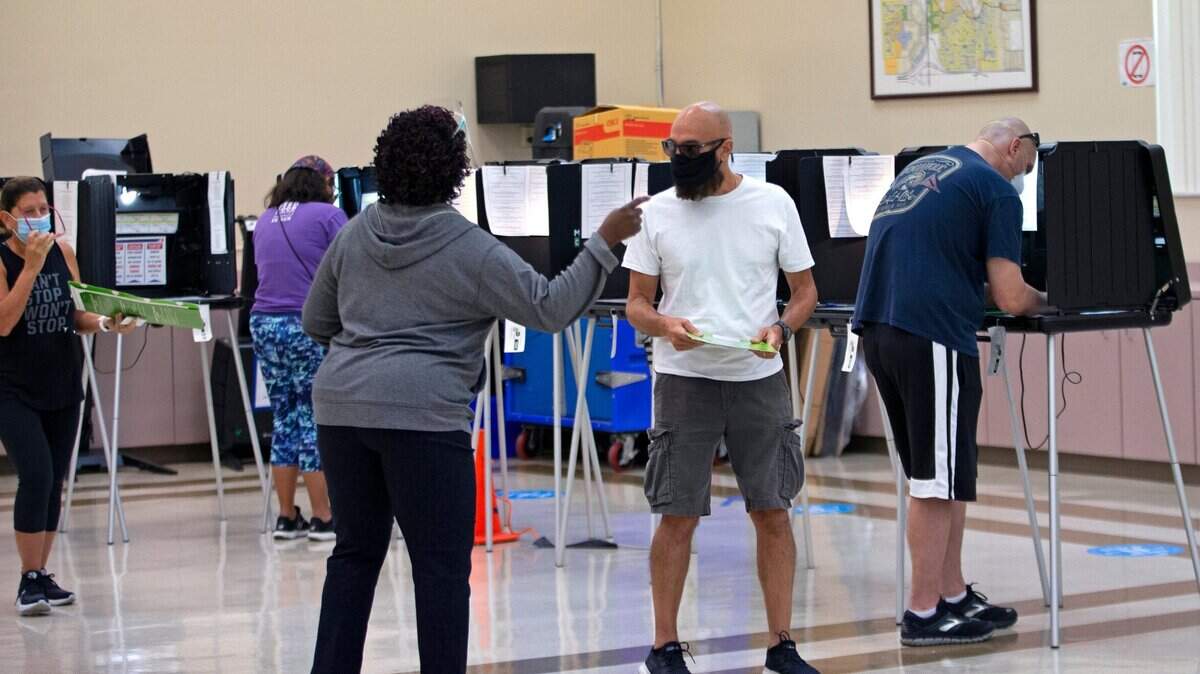 Una trabajadora electoral ayuda a una persona a votar durante las elecciones primarias en centro de votación de Miami Lakes Community Center, el 13 de agosto de 2020.