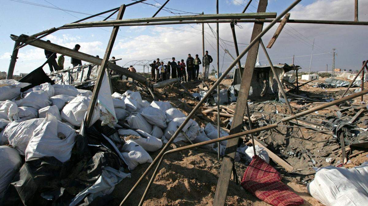 Un grupo de palestinos observa los daños ocasionados por un ataque aéreo israelí en Rafah, al sur de la franja de Gaza, en represalia al ataque con misil lanzado ayer desde Palestina.