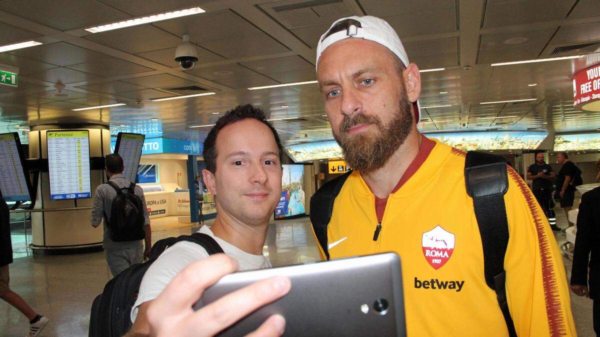 El jugador del AS Roma Daniele De Rossi se hace fotografías con los aficionados a su llegada al aeropuerto Leonardo da Vinci, de Roma,  el 18 de septiembre de 2018.