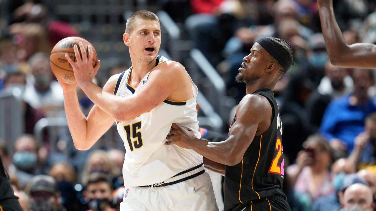 El centro de los Nuggets Nikola Jokic (izq.) trata de pasar la pelota ante la marca de Jimmy Butler, del Heat de Miami, en el partido celebrado el 8 de noviembre de 2021 en Denver.