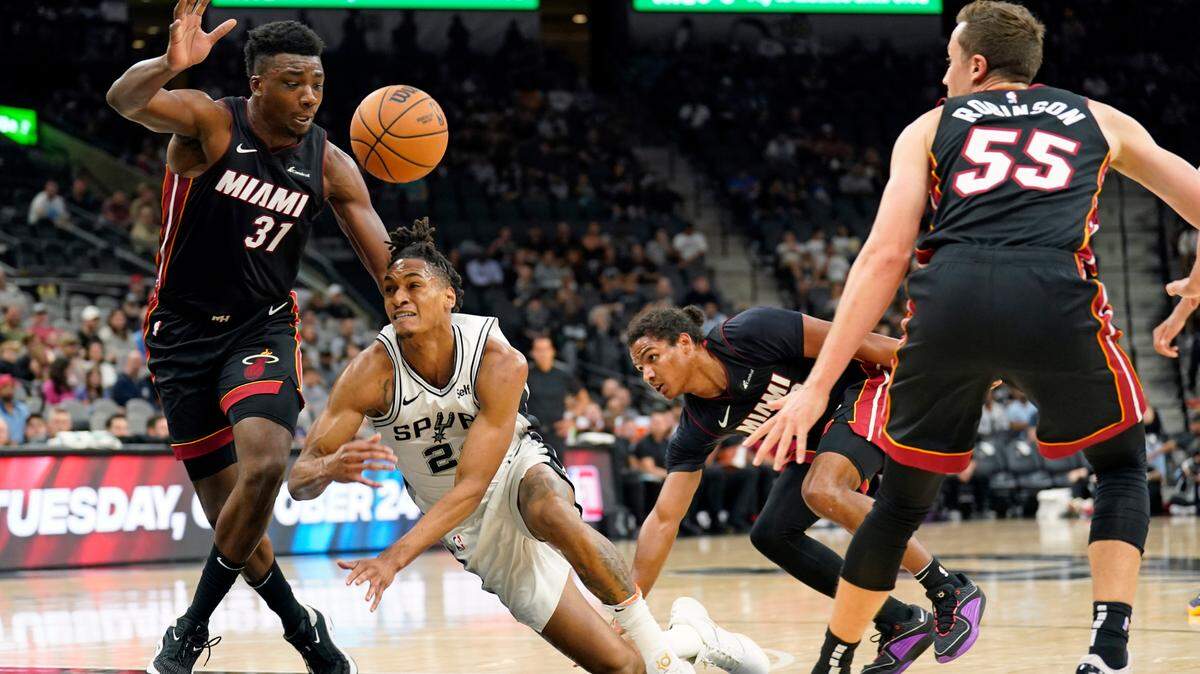 El guardia de San Antonio Spurs Devin Vassell (24) pierde el control del balón mientras lo defiende el centro de Miami Heat Thomas Bryant (31) , el armador Dru Smith (9) y el escolta Duncan Robinson durante la primera mitad en Frost Bank Center, este 13 de octubre de 2023; San Antonio, Texas.
