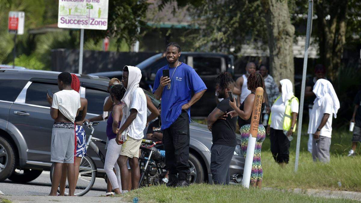 Residentes se congregan a varias cuadras de la tienda Dollar Store en donde un hombre blanco mató a tres personas, en Jacksonville, Florida, el sábado 26 de agosto de 2023.