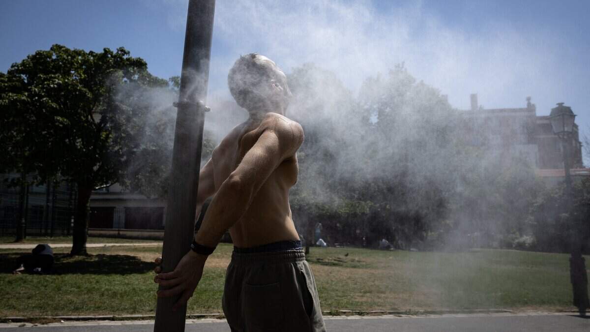 Un hombre se refresca en una fuente de niebla en París el 24 de junio de 2026, mientras una ola de calor afecta a Francia.