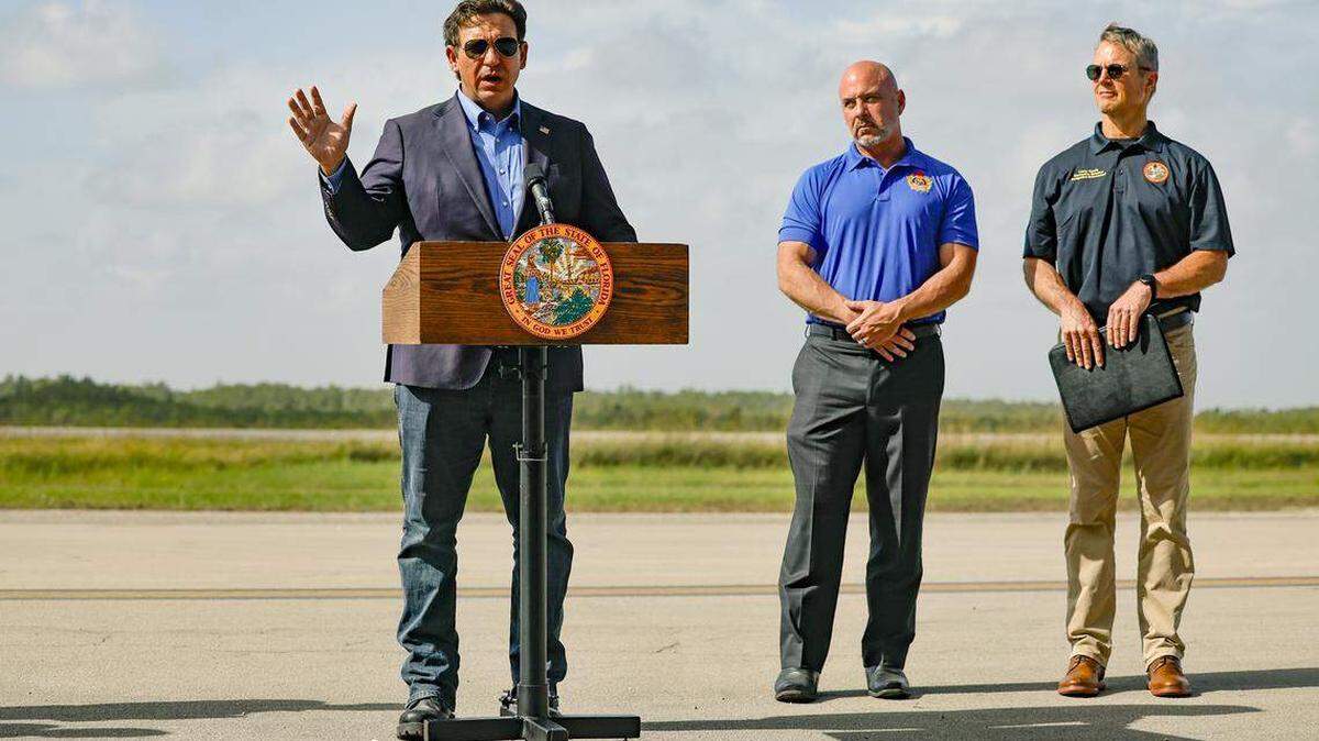 El gobernador Ron DeSantis habla con los periodistas durante una conferencia de prensa en la pista de aterrizaje de Alligator Alcatraz en Ochopee, Florida, el viernes 25 de julio de 2025. Junto al gobernador, Blaise Ingoglia, director financiero del Departamento de Servicios Financieros de la Florida, y Larry Keefe, director ejecutivo de la Junta Estatal de Control de Inmigración de la Florida.