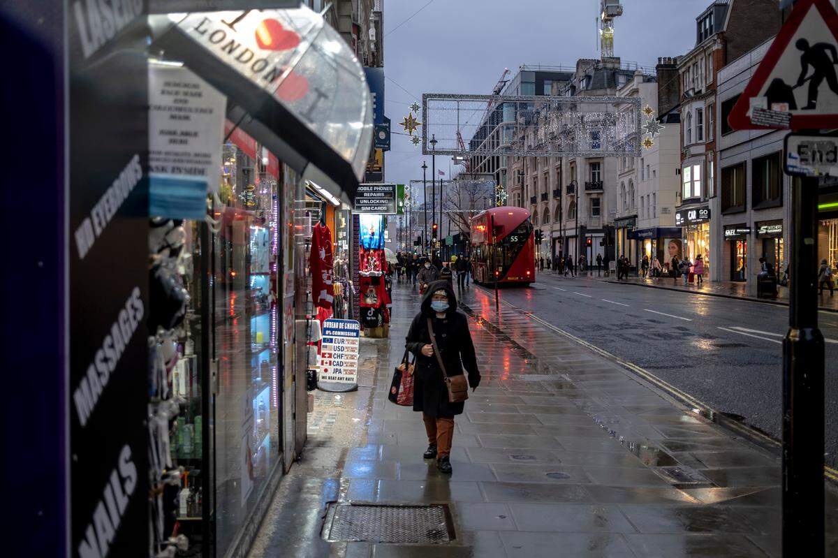 Una mujer camina por una calle húmeda por la lluvia en Oxford el primer día de restricciones de nivel 3 en Londres. Estas restricciones podrían estar en vigor durante mucho tiempo.