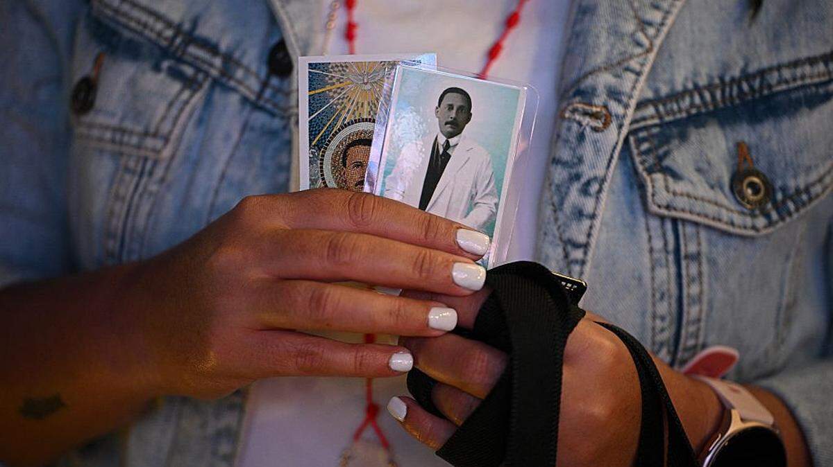 A catholic faithful holds images of Venezuelan docto Jose Gregorio Hernandez during the canonization ceremony at the Nuestra Senora de la Candelaria church in Caracas on October 19, 2025. (Photo by Federico PARRA / AFP) (Photo by FEDERICO PARRA/AFP via Getty Images)
