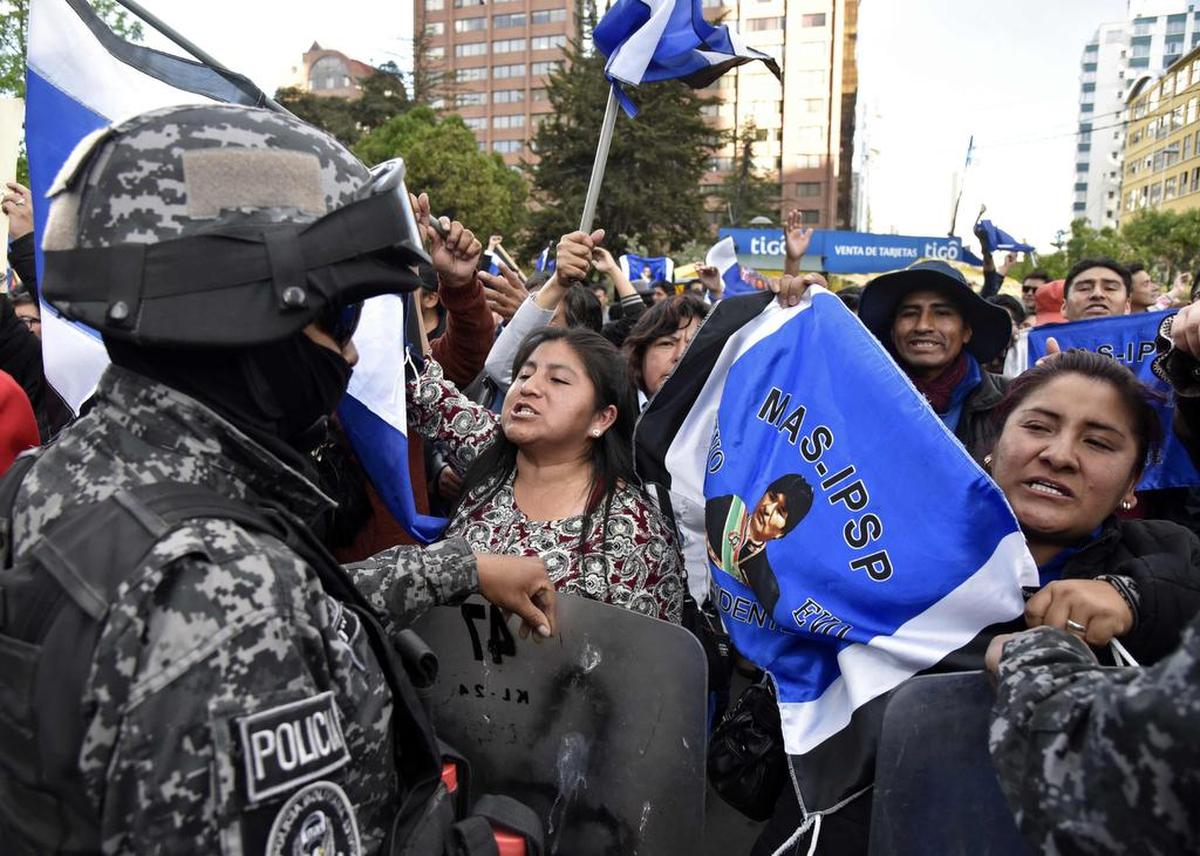 Supporters of Bolivian President and candidate Evo Morales are being contained by security forces as they shout slogans against supporters of the candidate of the ‘Comunidad Ciudadana’ party, former President Carlos Mesa, as both groups gather outside the Supreme Electoral Tribunal in La Paz, on Oct. 21, 2019.