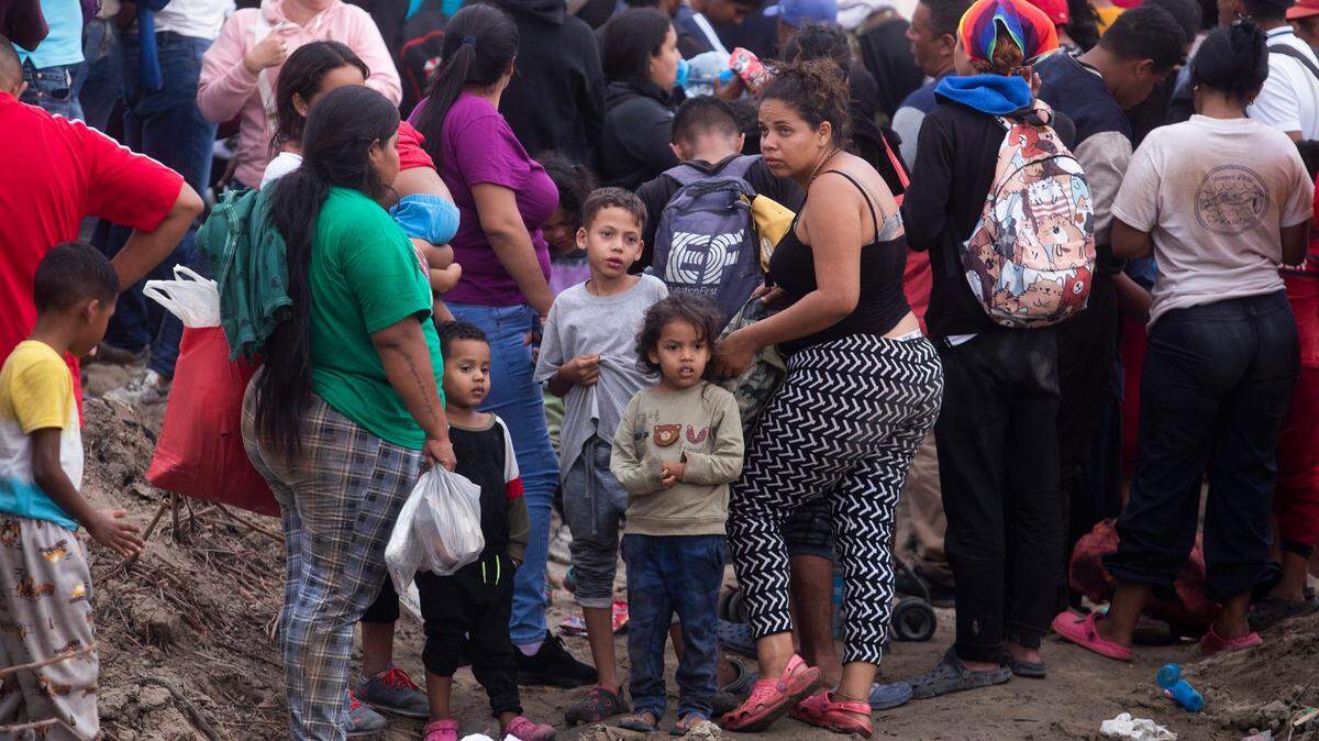 Dozens of migrants wait on the north side of the Rio Grande in September to see if the Texas National Guard will allow them to surrender to U.S. border authorities.