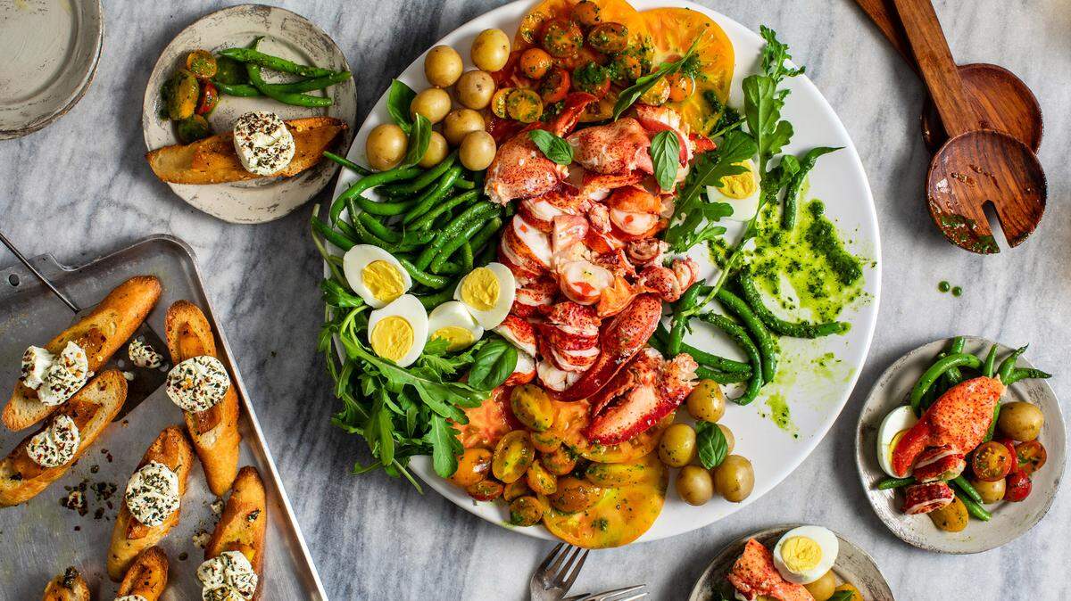 Pan tostado con pimiento asado y queso de cabra con hierbas, a la izquierda, y ensalada de langosta con ejotes, tomates y albahaca, al centro.
