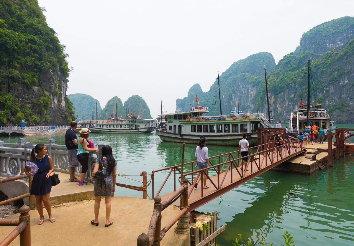Turistas subiendo a los barcos que hacen un recorrido por la impresionante Bahía de Ha Long.