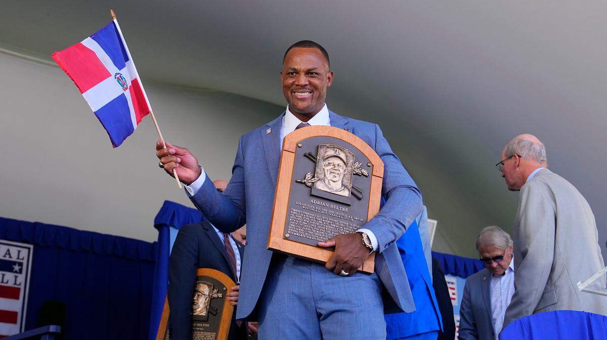 El expelotero Adrián Beltré posa con una bandera dominicana y la placa que lo acredita como miembro del Salón de la Fama de Grandes Ligas, en la ceremonia efectuada el 21 de julio de 2024 en Cooperstown, Nueva York.