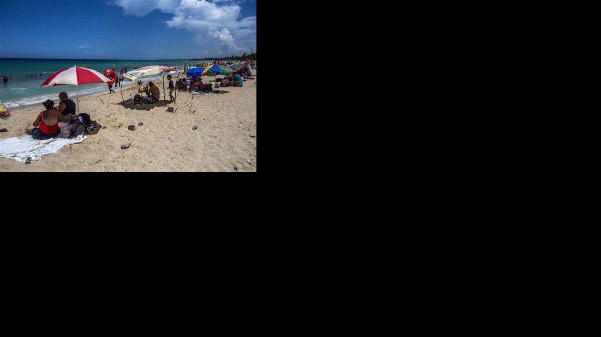 Banistas sentados en primera línea de playa en medio de latas vacías y basura cerca de La Habana, en Cuba, el 18 de agosto de 2016. (AP Foto/Desmond Boylan) 