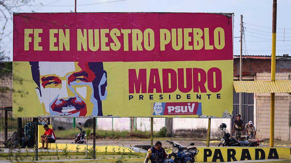 PUERTO CABELLO, VENEZUELA - DECEMBER 18: A motorcyclist rests under a banner in support of President of Venezuela Nicolas Maduro during a walk around the outskirts of the 'El Palito' refinery on December 18, 2025 in Puerto Cabello, Venezuela. President Trump stated on December 17th that Venezuela took away oil rights from the US. Trump's administration has sanctioned Venezuelan oil with blockades, while many US Navy units are deployed off the coast of Venezuela under the premise of combating the drug cartels. (Photo by Jesus Vargas/Getty Images)