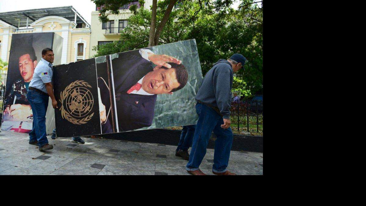 Empleados de la Asamblea Nacional retiran una foto del difunto presidente venezolano Hugo Chávez, este martes 6 de enero en Caracas. 