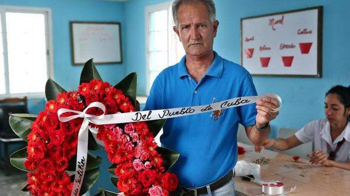 Fotografía fechada el 23 de mayo de 2018 que muestra al informático Carlos Parra mientras exhibe la cinta de una corona de flores escrita manualmente por él, durante una entrevista con Efe en la provincia de Holguín (Cuba).