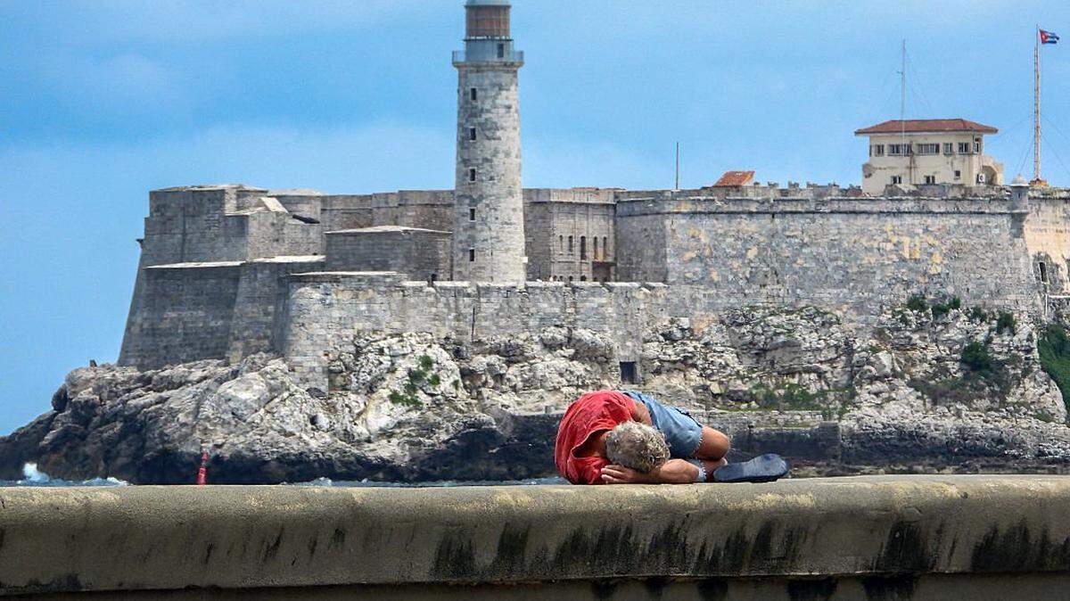 A man sleeps on Havana's Malecon waterfront on October 2, 2025. Poverty levels have risen sharply as Cuba faces its worst economic crisis in three decades, characterized by severe shortages of food, medicine, and fuel, along with daily power outages. (Photo by ADALBERTO ROQUE / AFP) (Photo by ADALBERTO ROQUE/AFP via Getty Images)