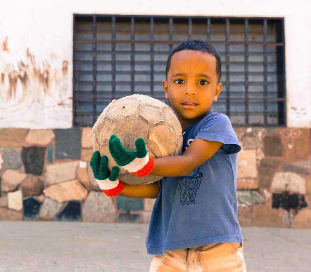 Jesús Urdaneta, de 3 años, sostiene un balón de fútbol con los guantes que recibió de un voluntario de Pasión Petare. Le gusta tanto el fútbol que pasa casi todo el día pateando la pelota en la calle.