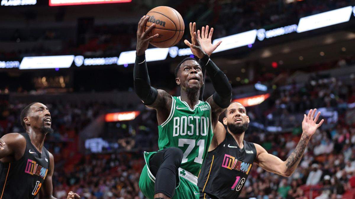 El jugador de los Celtics de Boston Dennis Schroder entra al aro ante la marca de Bam Adebayo (izq.) y Caleb Martin, del Heat, en el partido celebrado el 4 de noviembre de 2021 en el FTX Arena en Miami.