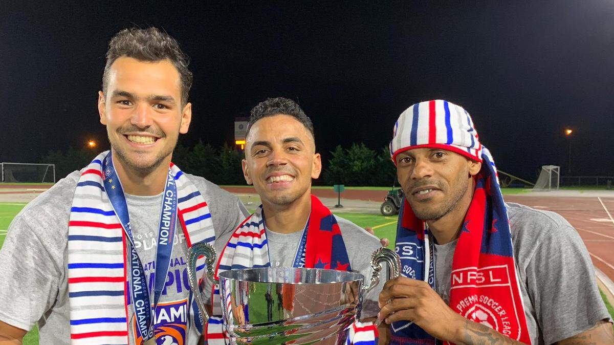 Darío Suárez, junto Héctor “el Chino’’ Morales (izq.) y Arielito Martínez (der.) posan con la copa tras procamarse con el Miami FC campeones de la NPSL, el pasado 3 de agosto en Nueva York.