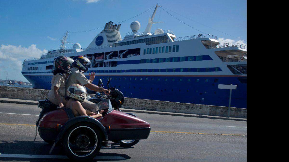 En esta foto de archivo de diciembre 2013,  tres personas  en una motocicleta  pasan frente a un crucero atracado en el puerto de La Habana, Cuba.   AP / Ramón Espinosa