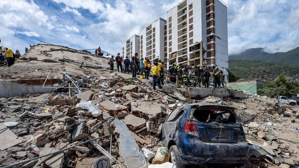 Rescuers work on the rubble of a collapsed building near a damaged vehicle in Caraballeda, La Guaira state, Venezuela, on June 28, 2026, following earthquakes. Thousands of rescuers, relatives and volunteers dig day and night through mounds of concrete to find survivors of the earthquakes that struck Venezuela more than three days ago, leaving nearly 1,500 dead and tens of thousands missing. (Photo by Miguel MEDINA / POOL / AFP via Getty Images)