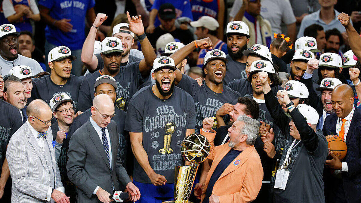 Karl-Anthony Towns (n.º 32), de los New York Knicks, y el propietario del equipo, James Dolan, celebran detrás del trofeo de campeonato Larry O’Brien tras la victoria ante los San Antonio Spurs en el quinto partido de las Finales de la NBA de 2026, disputado en el Frost Bank Center el sábado 13 de junio de 2026 en San Antonio, Texas.