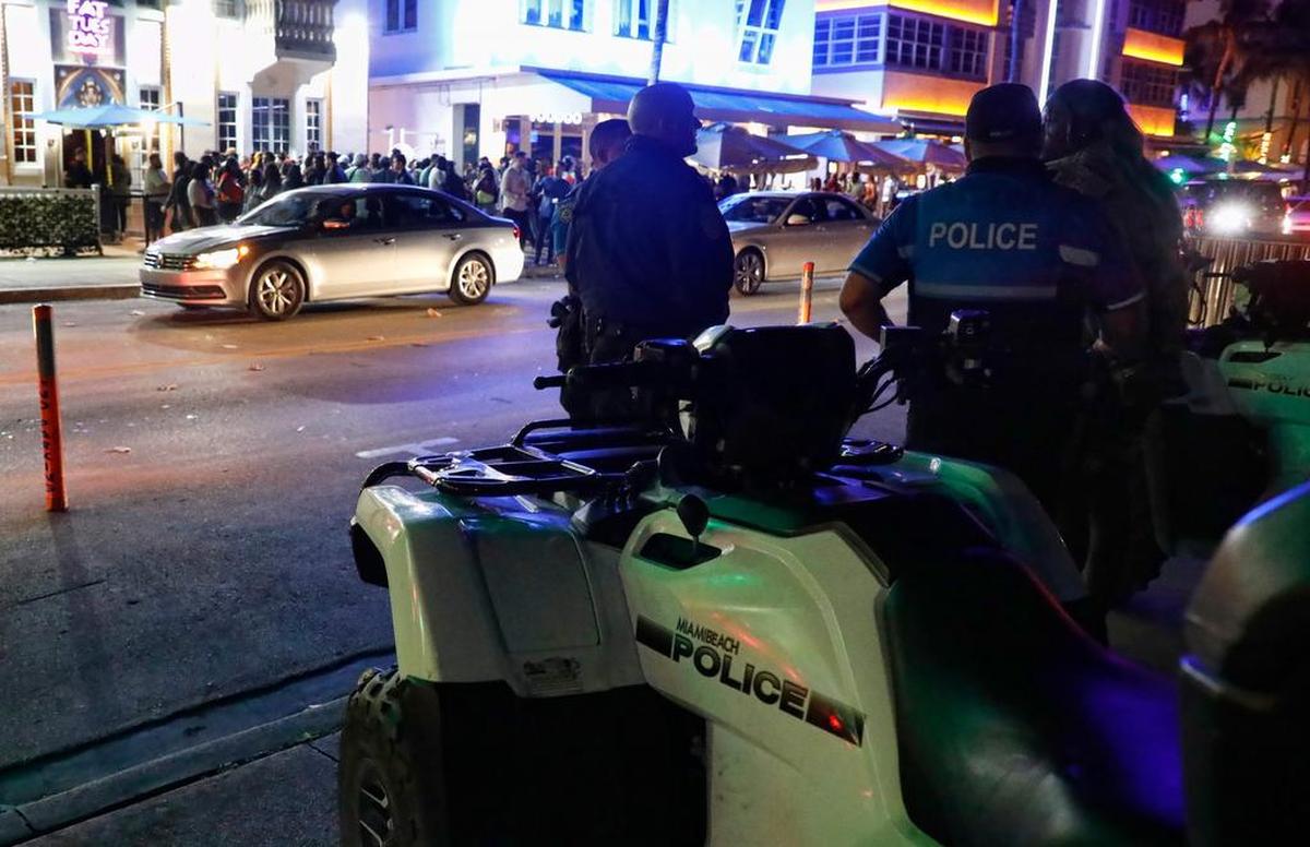 Miami Beach police officers stand across the street from the nightclubs and hotels on Ocean Drive during Spring Break 2019. The Miami Beach City Commission on Wednesday passed a law requiring Ocean Drive bars to hire off-duty police officers on weekends.