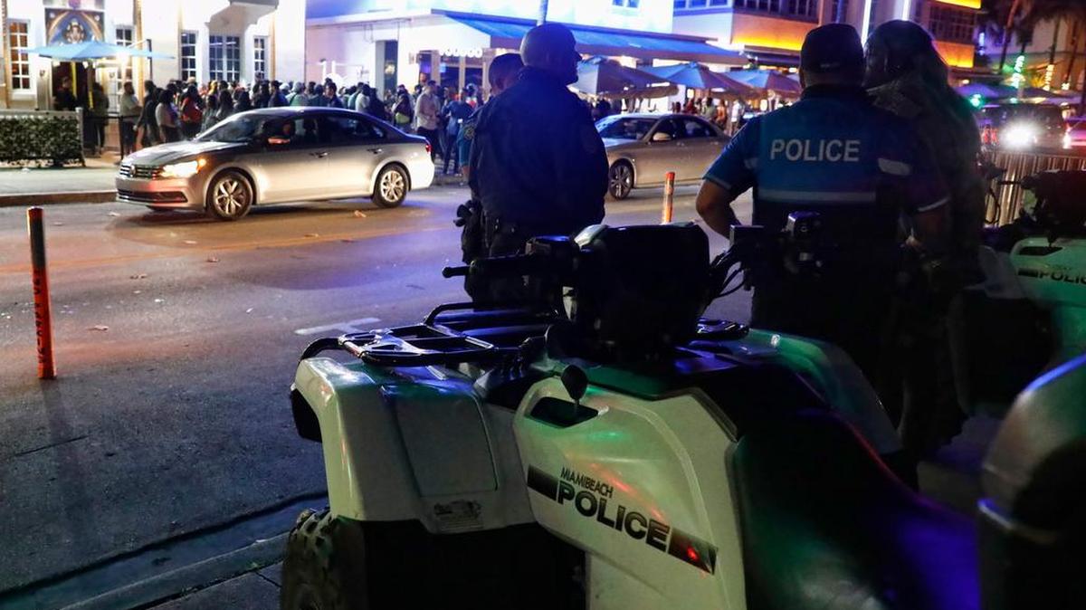 Miami Beach police officers stand across the street from the night clubs and hotels on Ocean Drive on Friday.
