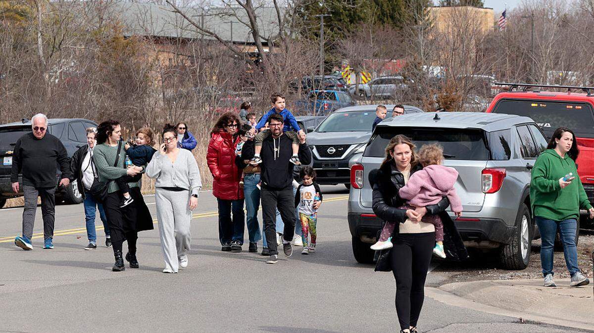 Familias se retiran del exterior de la sinagoga Temple Israel, después de que un hombre armado con un fusil estrellara su camioneta contra el edificio en West Bloomfield, Michigan, el 12 de marzo de 2026. 