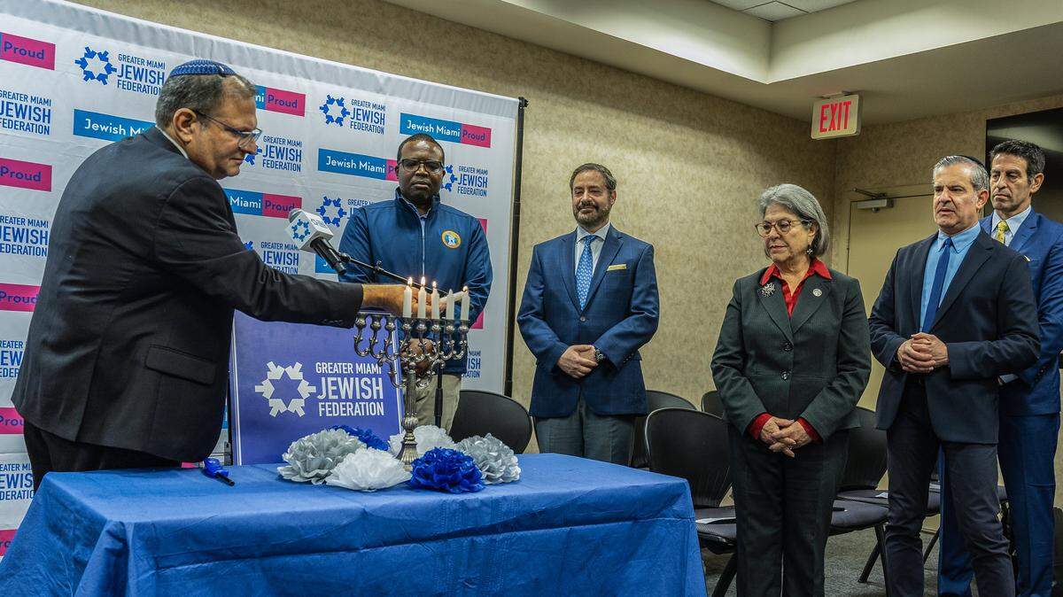El rabino Frederick “Fred” Klein enciende las velas de Janucá mientras alcaldes locales, entre ellos la alcaldesa de Miami-Dade, Daniella Levine Cava (centro), el alcalde de Miami Beach, Steven Meiner (segundo desde la derecha) y el alcalde de North Miami Beach, Michael Joseph (extremo izquierdo), y líderes comunitarios se unen para denunciar el antisemitismo en el sur de Florida. 