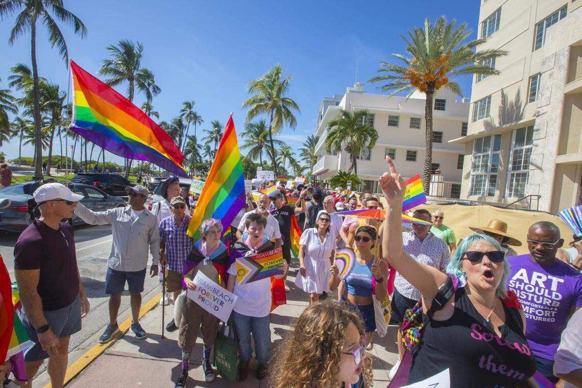 Manifestantes portando banderas arcoíris y carteles con las leyendas “Miami Beach Orgulloso por Siempre” y “No Será Borrado” marchan durante la Marcha Orgulloso por Siempre en Ocean Drive, Miami Beach, Florida, el domingo 31 de agosto de 2025, celebrada tras la orden de las autoridades estatales de retirar el cruce peatonal del Orgullo LGBTQ de la ciudad.
