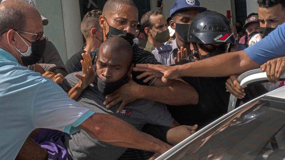 Cuerpos represivos del gobierno de Díaz Canel meten a la fuerza en una carro a un manifestante durante las protestas del 11 de agosto en La Habana.