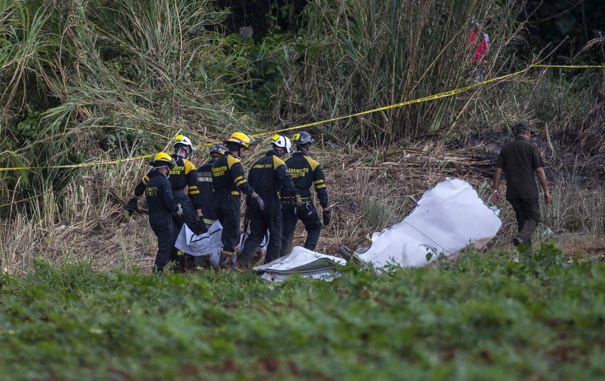 Bomberos cargan una bolsa para cadáveres que contiene restos humanos recuperados en el sitio donde un Boeing 737 cayó con más de 100 pasajeros a bordo, en La Habana, Cuba, el viernes 18 de mayo de 2018.
